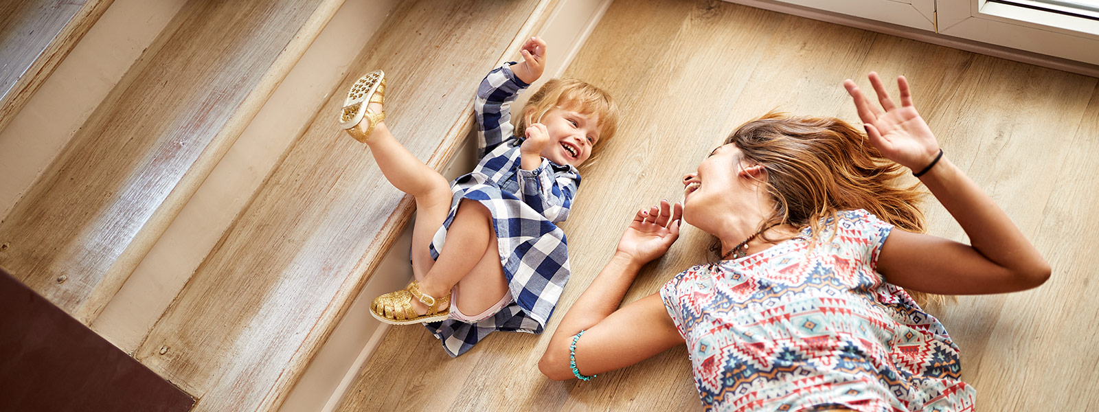 Mother and daughter lying on the floor looking at each other and laughing