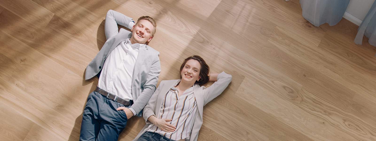A young couple laying on the floor looking up and smiling
